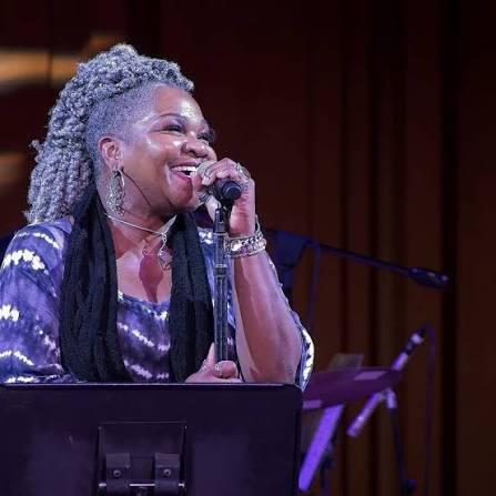Trina Meade laughing at the microphone during a seated performance